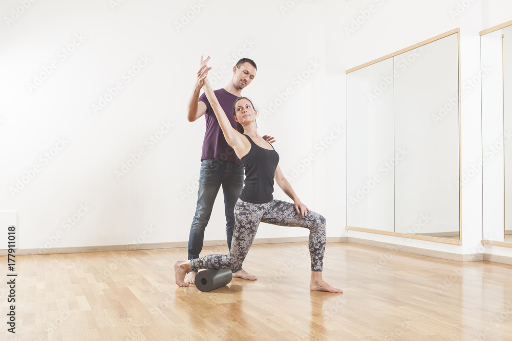 Pilates instructor coaching a beautiful woman using foam roller Pilates instructor coaching a beautiful woman using foam roller