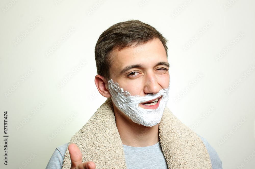 Young handsome man with towel on shoulders and foam board wink into mirror Young handsome man with towel on shoulders and foam board wink into mirror
