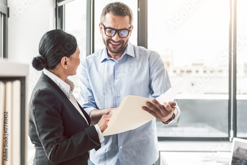 Cheerful manager checking work of colleague