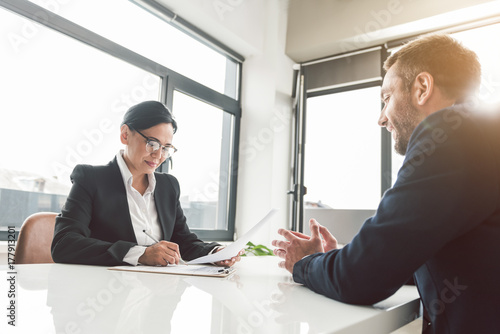 Fotografie Glad career girl speaking with beaming colleague