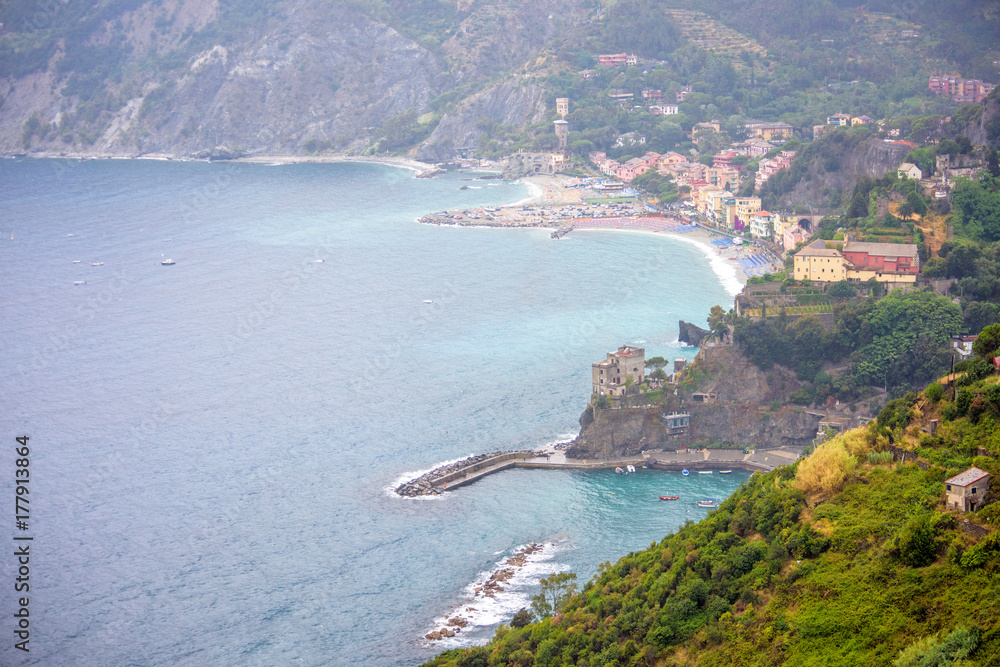 Aerial view to the beach and coastline of Monterosso al Mare, Cinque Terre, Italy. Houses, parked cars and beautiful green mountains.