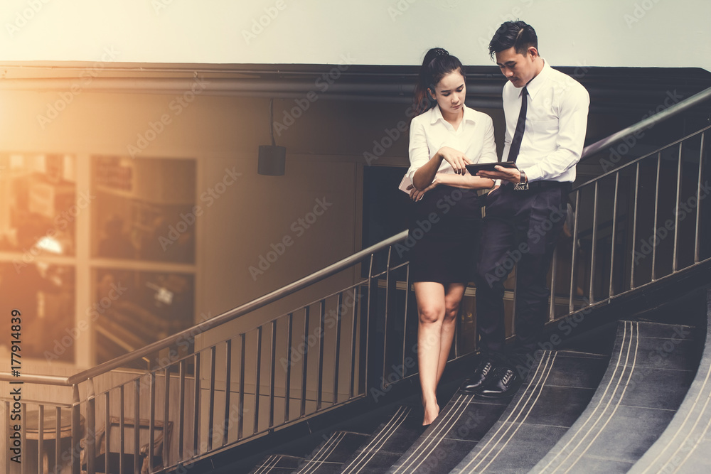 businessman and woman using tablet of working. Meetings the commercial activities in promoting. Together create a mutually beneficial on stairs.outside.Vintage tone businessman and woman using tablet of working. Meetings the commercial activities in promoting. Together create a mutually beneficial on stairs.outside.Vintage tone