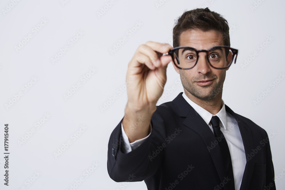 Businessman holding spectacles up to camera, smiling Businessman holding spectacles up to camera, smiling
