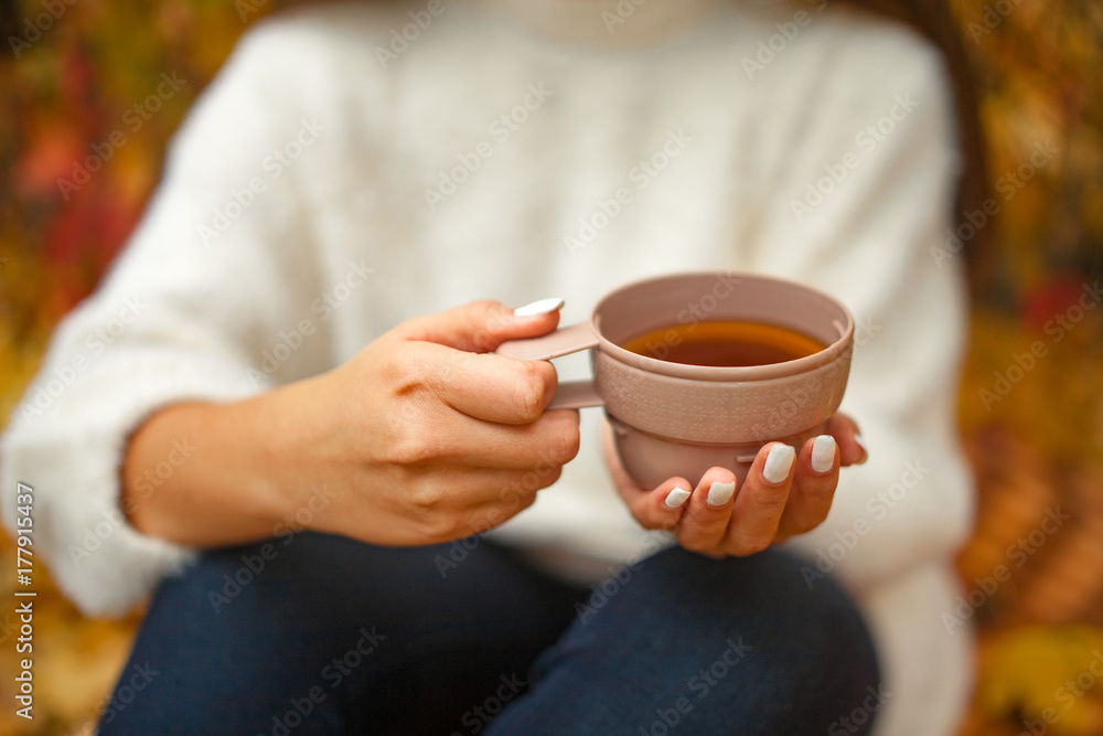 Female hands hold cup of hot tea on outing in autumn. Close up. Female hands hold cup of hot tea on outing in autumn. Close up.