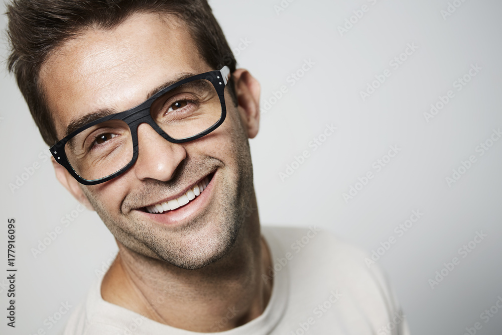 Handsome guy in glasses smiling to camera, studio