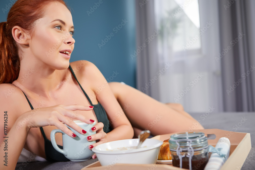 Beautiful happy redhead woman having breakfast in bed Beautiful happy redhead woman having breakfast in bed