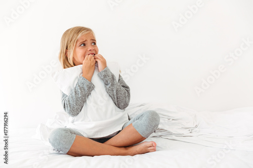 Portrait of a panicked little girl hugging pillow