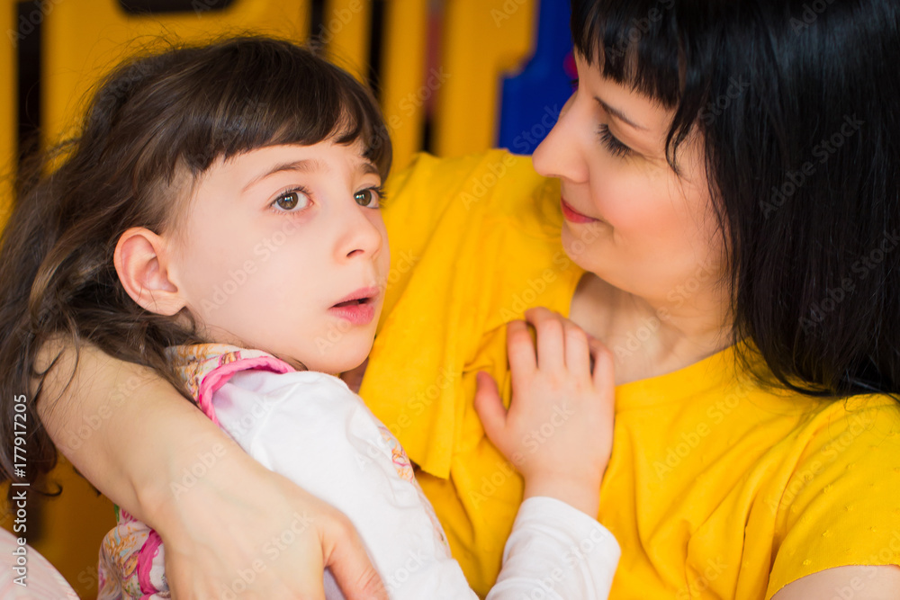 Portrait of little beautiful disabled girl who lying in her mother's arms in the room Portrait of little beautiful disabled girl who lying in her mother's arms in the room