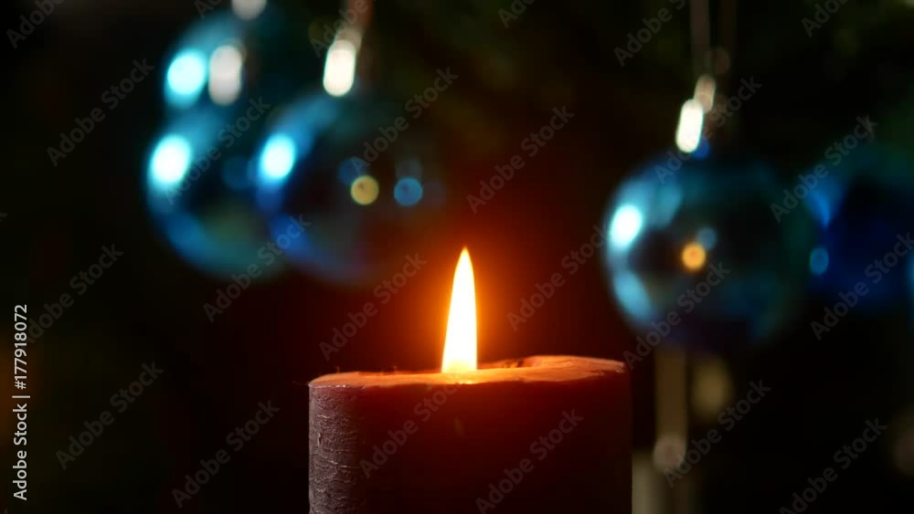 Christmas evening. The candle burns on the background of the New Year tree. Christmas evening. The candle burns on the background of the New Year tree.