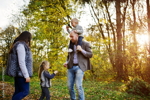 Happy caucasian family of mom dad and little girl with boy at majestic autumn fall forest.