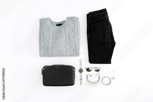 Women's fashion clothes and accessories on white background. Flat lay female styled look with warm sweater, jeans, purse, watch, sunglasses. Top view.