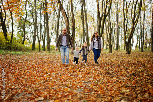 Happy caucasian family of mom dad and little girl with boy at majestic autumn fall forest.