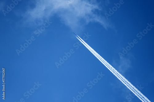 Aircraft with condensation trails on blue sky