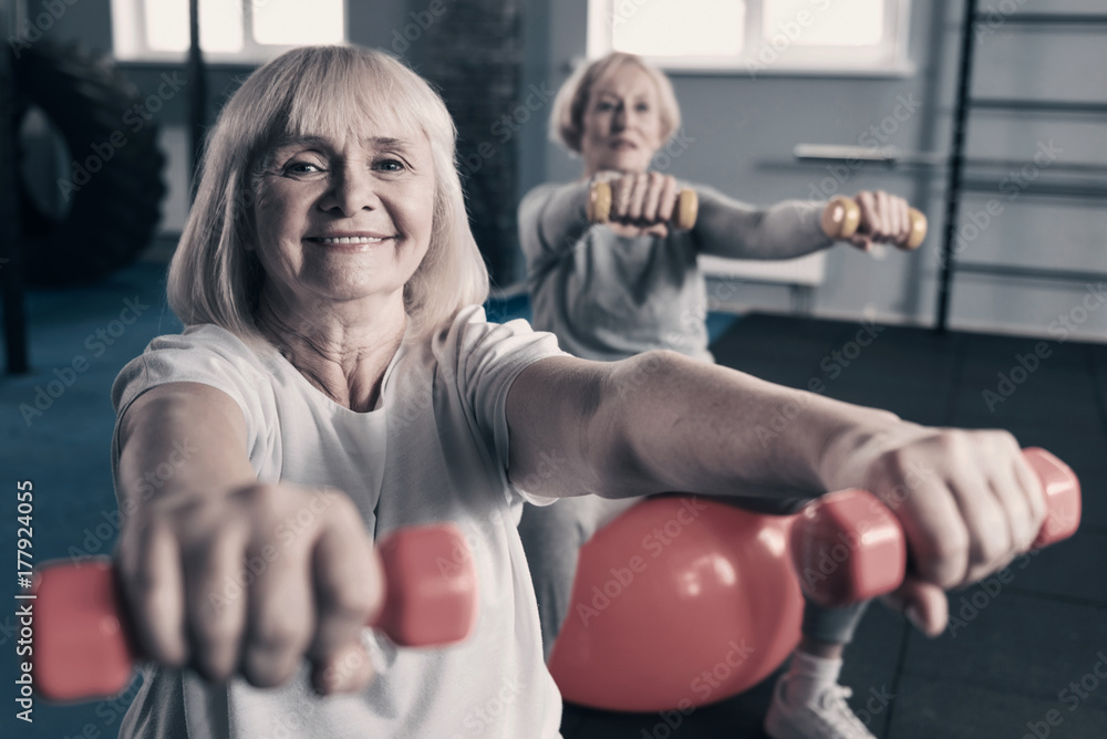 Elderly woman exercising with dumbbells in gym