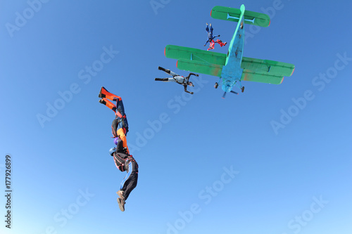 Skydivers are jumping out of a biplane.