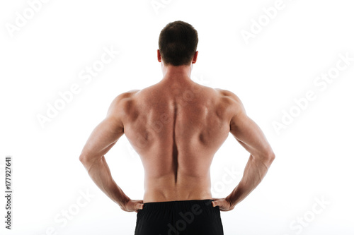 Back view of young athletic sports man standing with hands on his waist