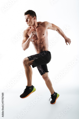 Full length portrait of young athletic man running over white background