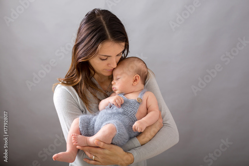 Young mother, caressing her newborn baby boy, holding him in her arms and smiling