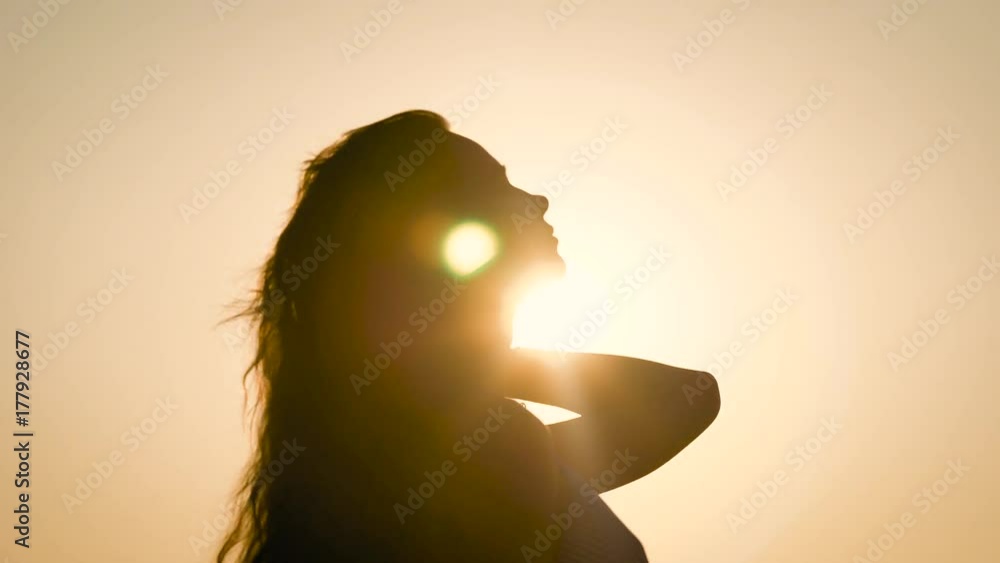 Side view of anonymous woman posing in back light on sky background. Side view of anonymous woman posing in back light on sky background.