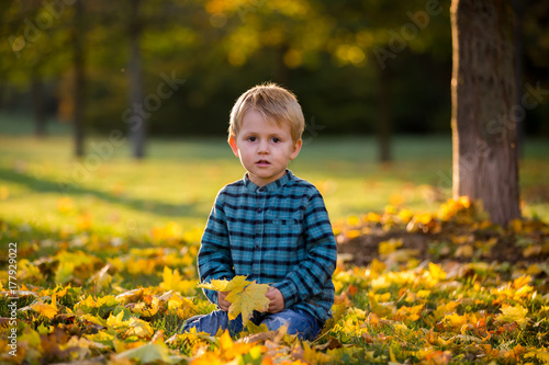 Adorable little boy with teddy bear in the park on an autumn day