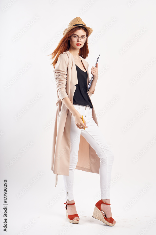 girl in a hat wearing a black T-shirt and a light coat posing on a light background girl in a hat wearing a black T-shirt and a light coat posing on a light background