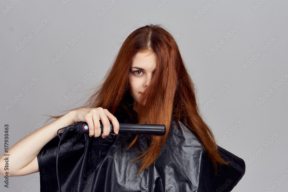 the girl the hairdresser leveles her hair on a gray background the girl the hairdresser leveles her hair on a gray background