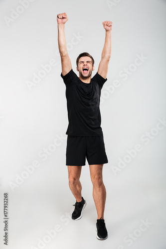 Full length portrait of a happy amused sportsman celebrating success