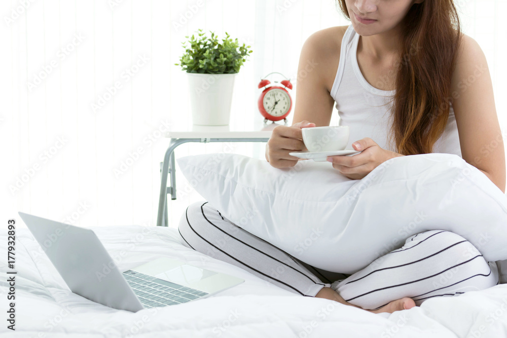 Happy casual beautiful woman working on a laptop sitting on the bed in the house. Happy casual beautiful woman working on a laptop sitting on the bed in the house.