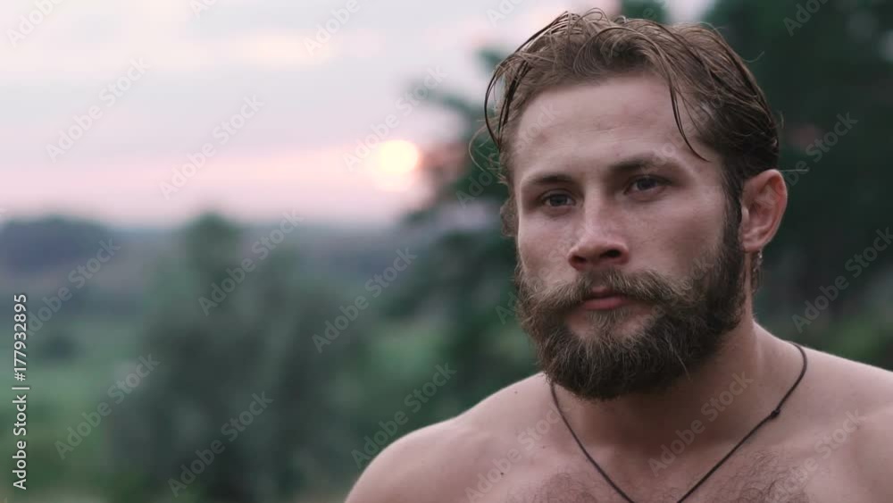 Portrait of free, beraded strong, blue-eyed man on nature. Slowly