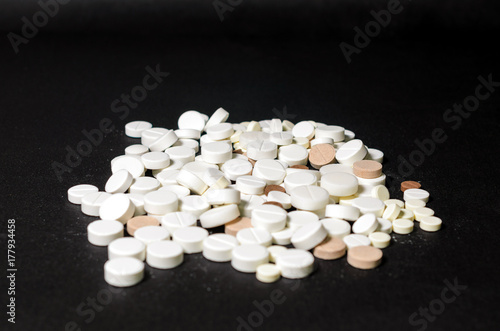 Handful of pills on a black background closeup top view