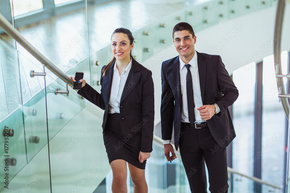 Two businesspeople talking as they walk into the office Two businesspeople talking as they walk into the office