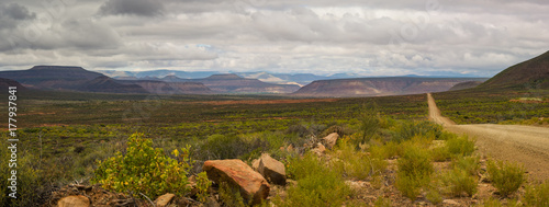 Canvas Print A Karoo country road in South Africa stretches out to the horizon with mountains