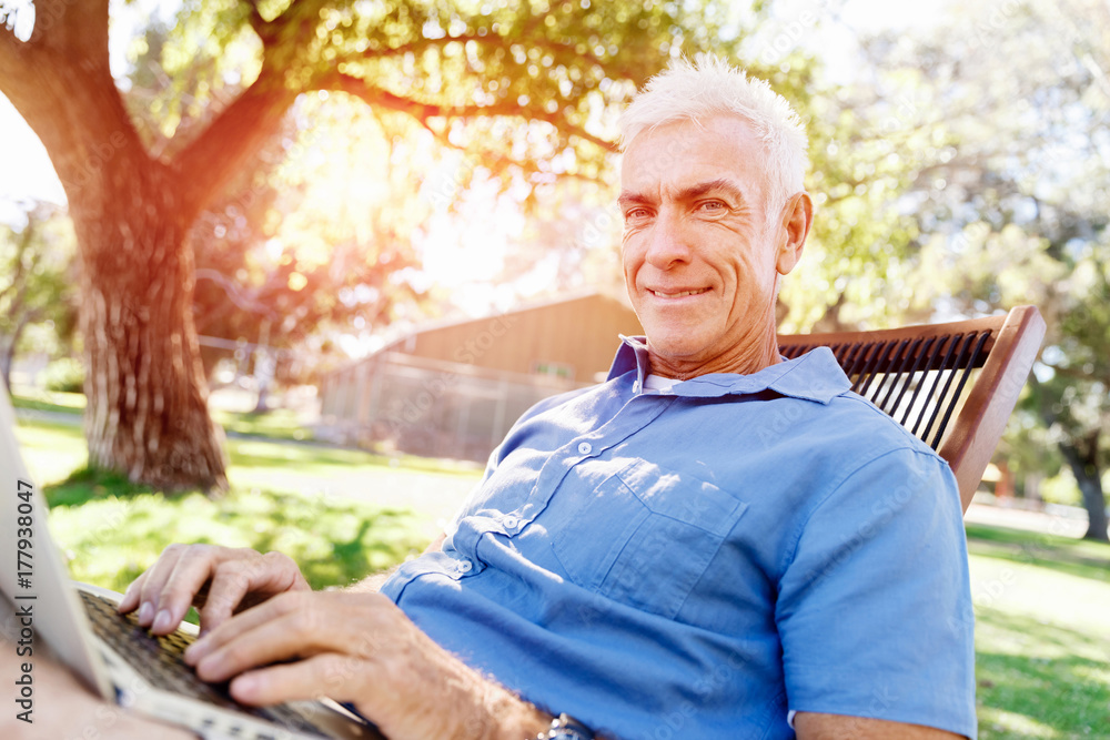 Senior man with notebook sitting in the park Senior man with notebook sitting in the park