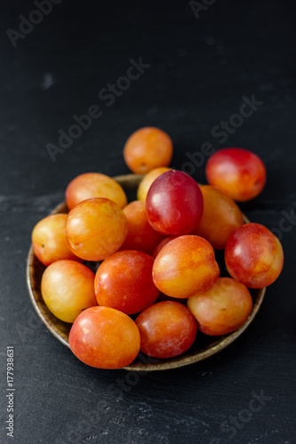 Top view of wild plums fruits on black stone background.