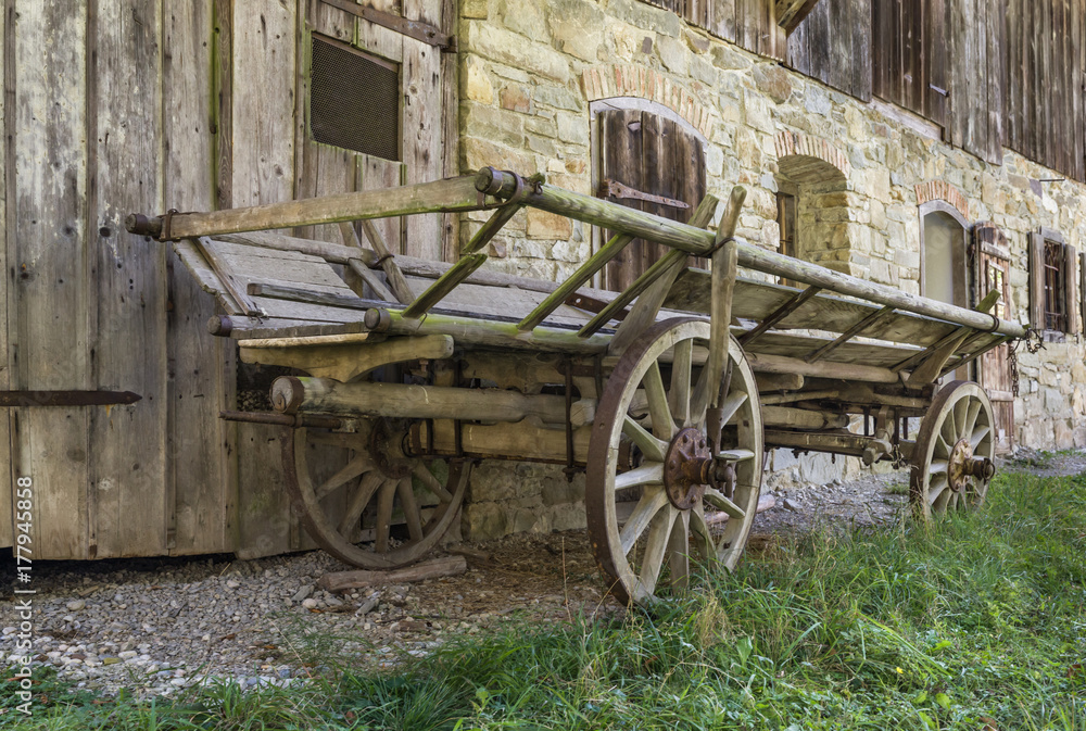 Historic wooden horse driven cart in front of an old farmhouse