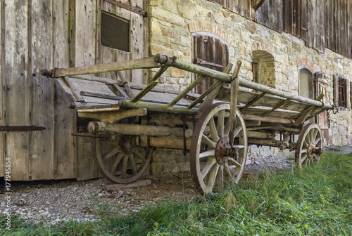 Historic wooden horse driven cart in front of an old farmhouse