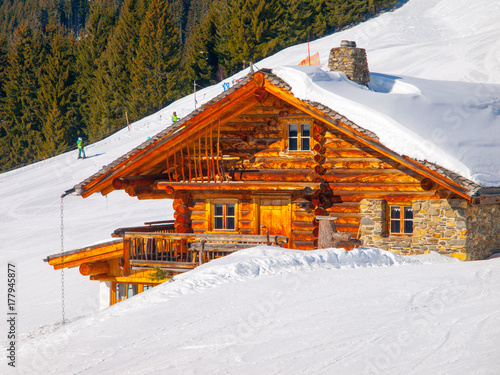 Traditional wooden mountain hut on sunny winter day. Alps, Europe.