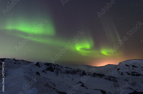 Snow covered the hills and in the sky stars, clouds and northern lights. © Moroshka