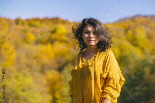 Beautiful young brunette enjoys a sunny day of autumn in nature