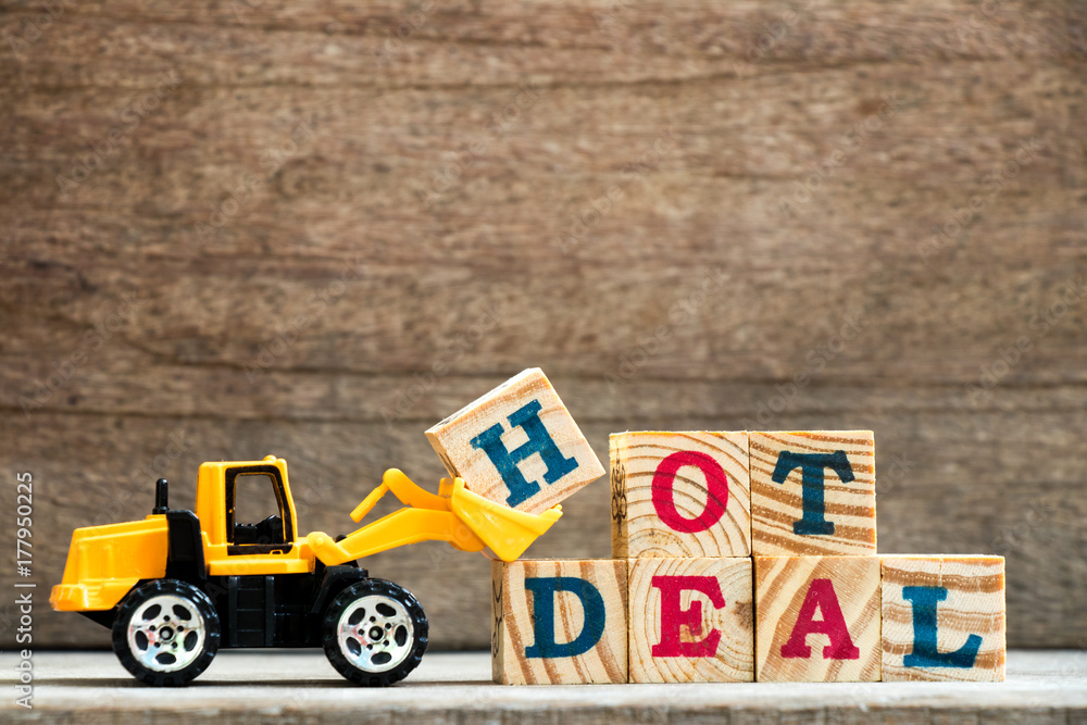 Obraz premium Toy plastic bulldozer hold letter block H to complete wording hot deal on wood background