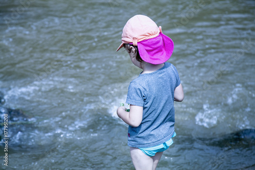 Fototapeta Naklejka Na Ścianę i Meble -  Little girl having fun by mountain  river at summer (Holiday, rest, happy childhood, games, nature concept)