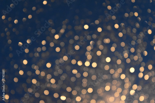 Glittering bokeh circular gold on blue background.