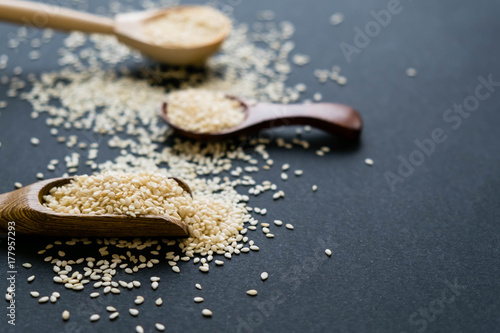 Organic natural sesame seeds wooden spoon. toasted sesame seeds. Raw, whole, unprocessed. Natural light. Selective focus. Close up on a black background. Top view, flat lay. copy space for text.
