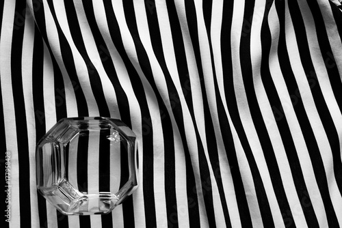 Black and white photo of a glass of old fashioned on a geometric background of lines