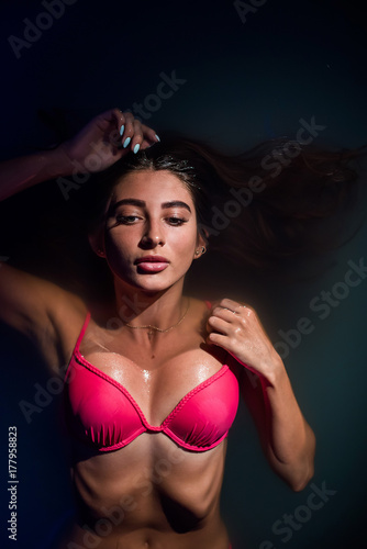 Beautiful tanned woman in pink swimwear relaxing in swimming pool spa © Михаил Решетников