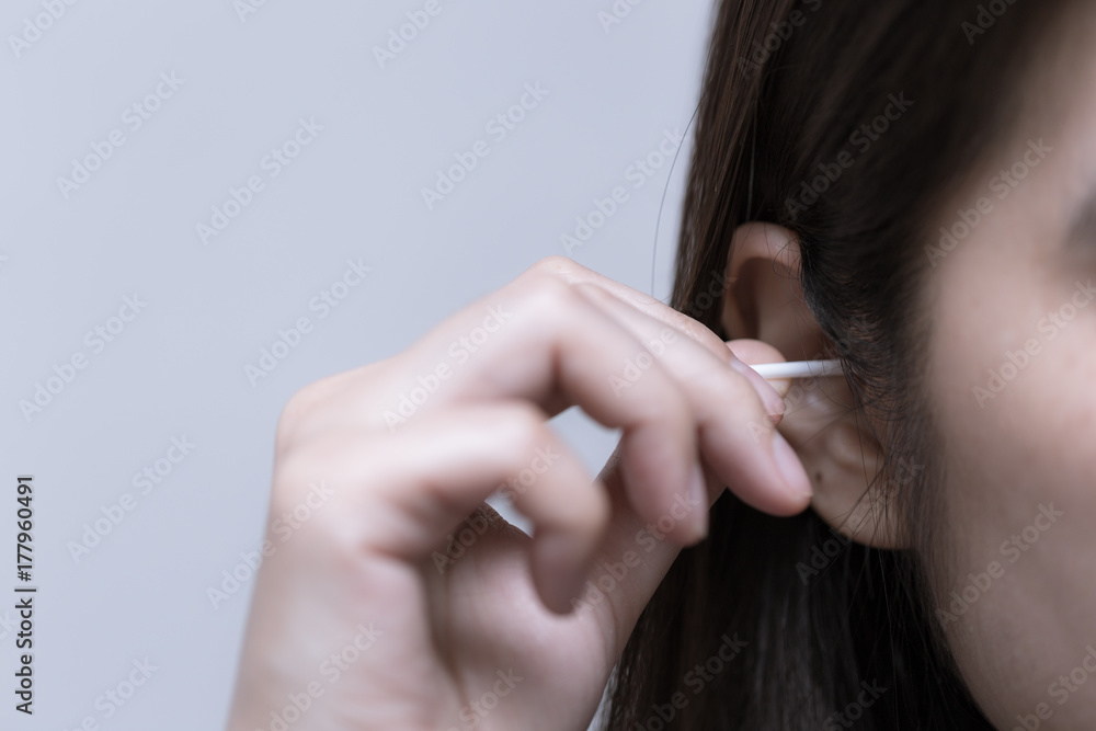 Young woman is using cotton bud with her ears, beauty concept Young woman is using cotton bud with her ears, beauty concept