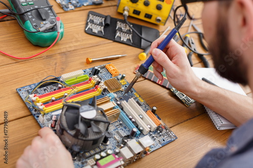 Wallpaper Mural Repairman soldering computer circuit in workshop Torontodigital.ca