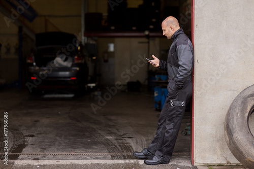 auto mechanic with smartphone at car service