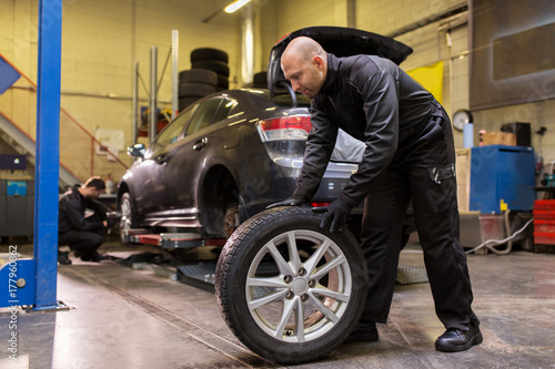 auto mechanic changing car tire at workshop