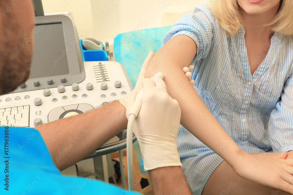 Doctor conducting ultrasound examination of patient's elbow in clinic Doctor conducting ultrasound examination of patient's elbow in clinic